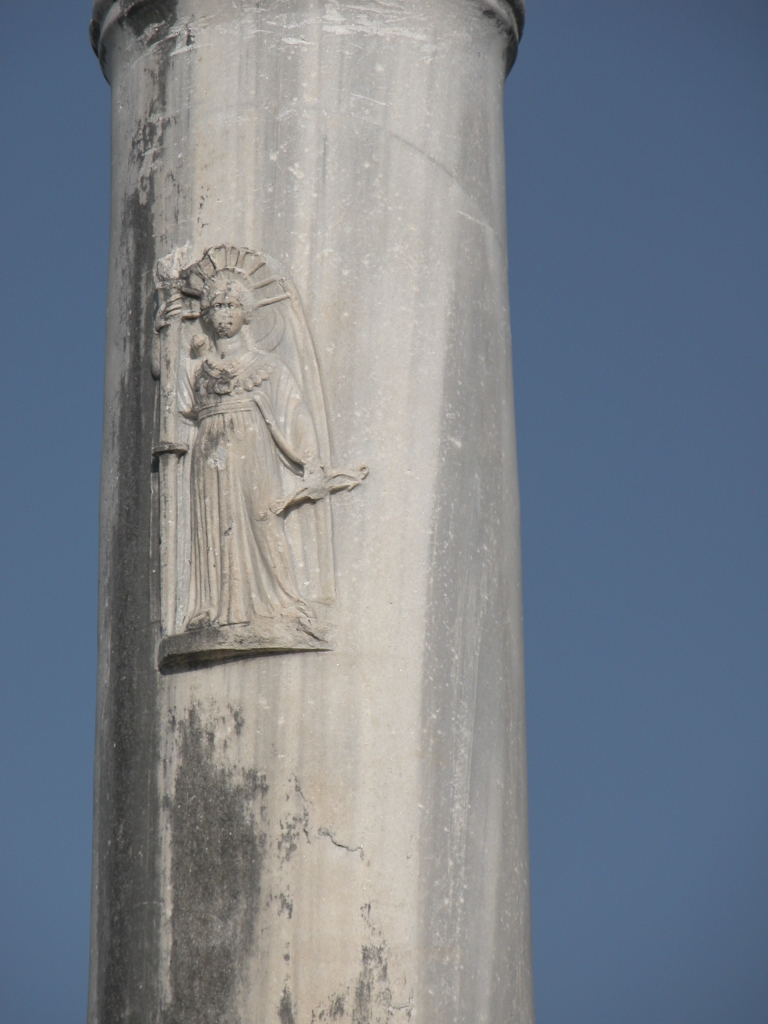Middle of Column
I'm guessing, on the basis of the bow in her hand, that the figure depicted here is the Greek goddess Artemis the Huntress.
